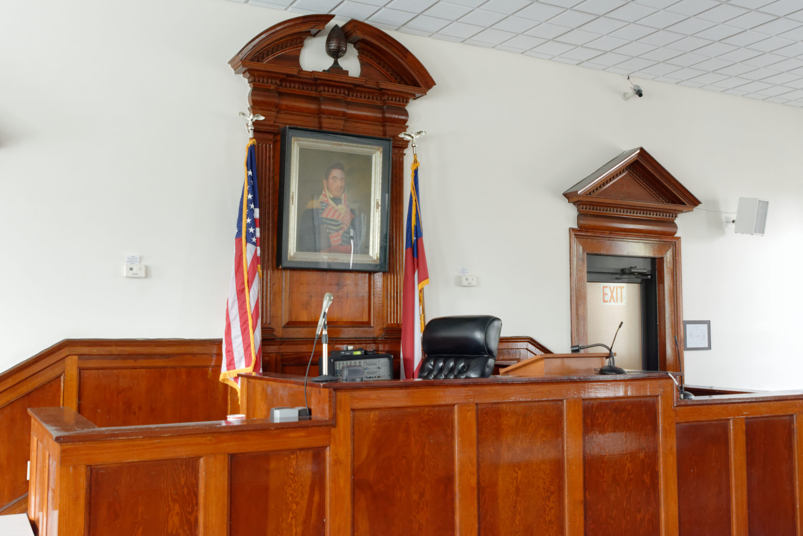 An empty ornate courtroom bench with multiple judicial chairs bathed in natural light
